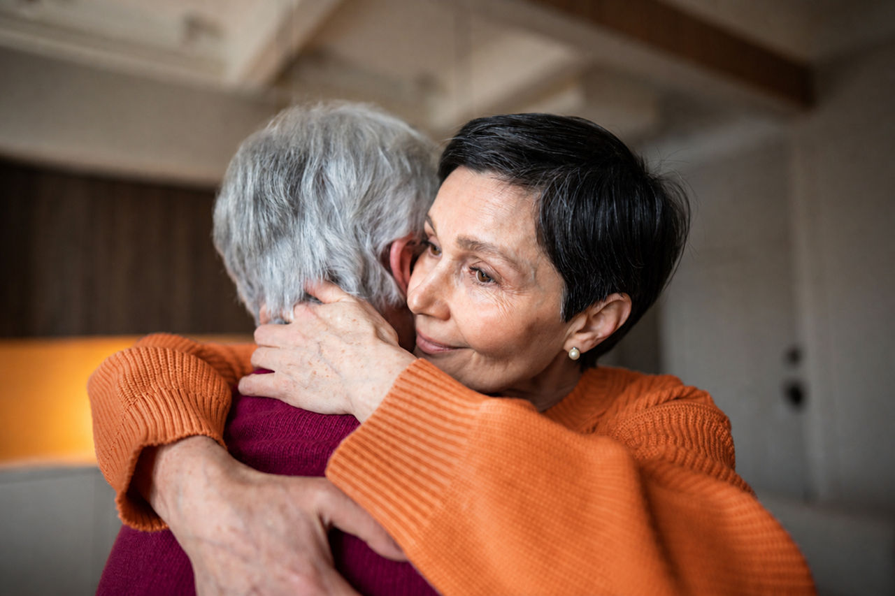 two women hugging on couch